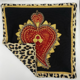 Decorative pillow with red heart design and leopard print border on a black background